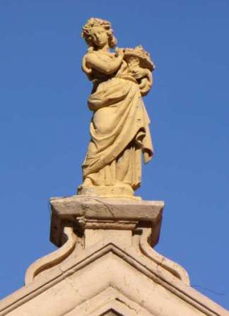 Detalle de la  figura femenina, alegoría de la Abundancia en la cornisa de la entrada principal
