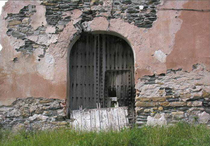 Puerta de acceso a la iglesia y restos del artesonado apoyado en ella.