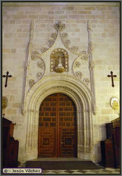 Puerta con decoración gótica y arco de medio punto. Sobre ella, hornacina con venera conteniendo la imagen de la Virgen.